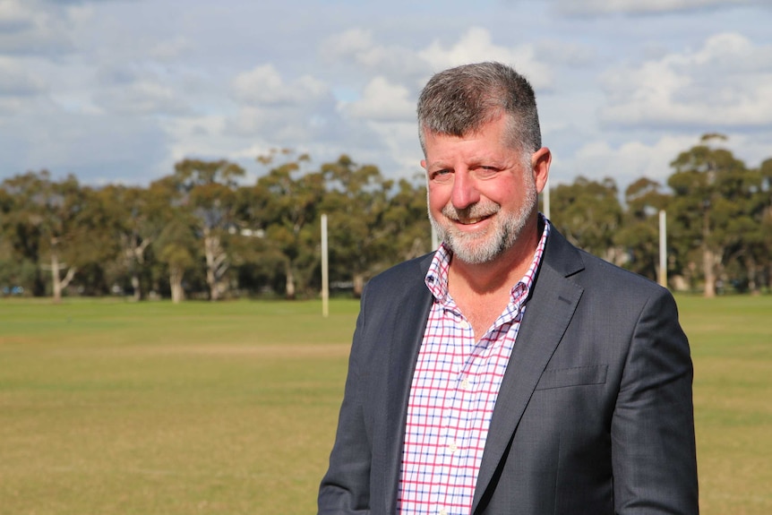 Tim Stollznow stands on a football oval