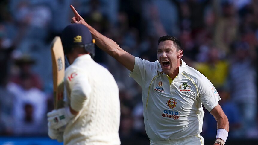 Australia bowler Scott Boland points as he runs and shouts. England batter Jack Leach stands in the foreground.