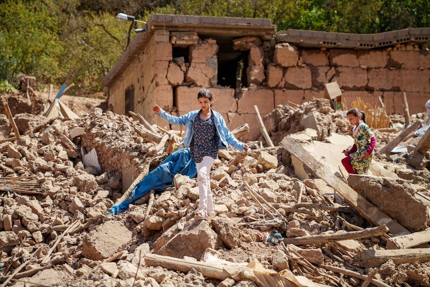 Two young girls, seen from a distance, walking on a pile of rubble