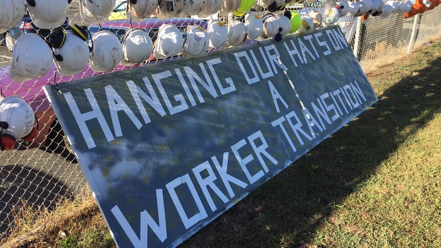 Dozens of hard hats with written messages attached to the fence of the Hazelwood power plant.