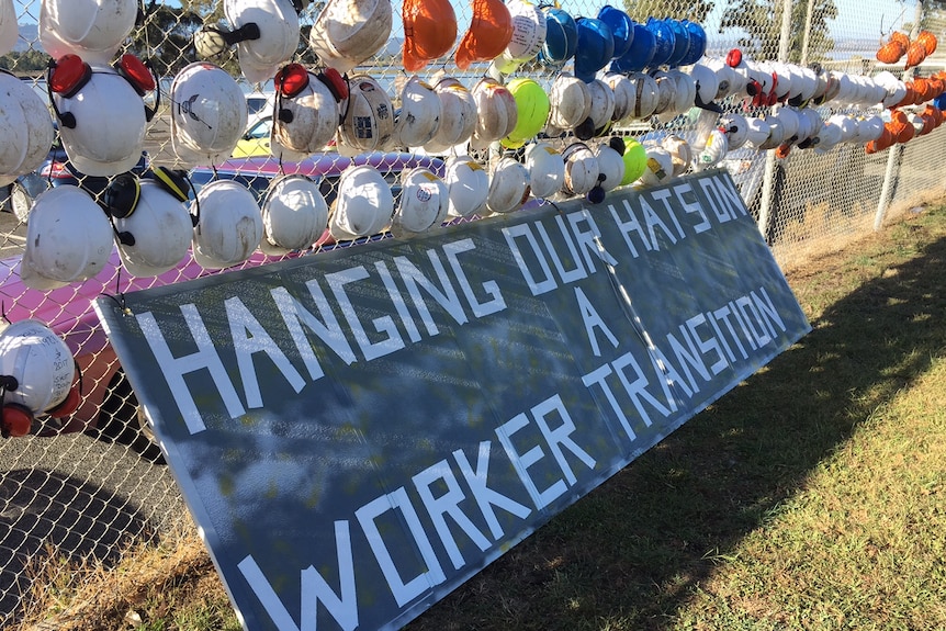Dozens of hard hats with written messages attached to the fence of the Hazelwood power plant.