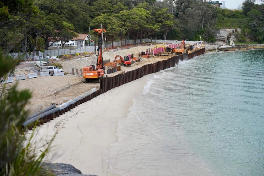 excavators and workers at nielsen park fixing a seawall damaged after a storm