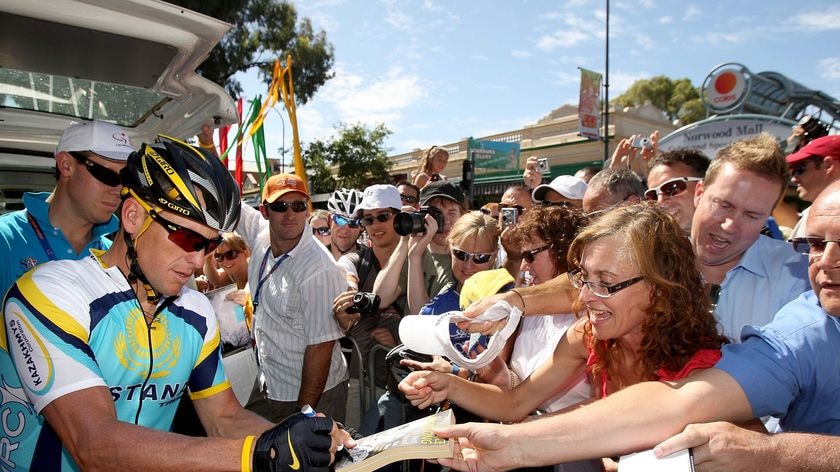 Lance Armstrong signs autographs before the start of stage one