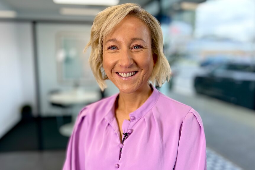 Smiling woman in purple shirt with short blonde hair