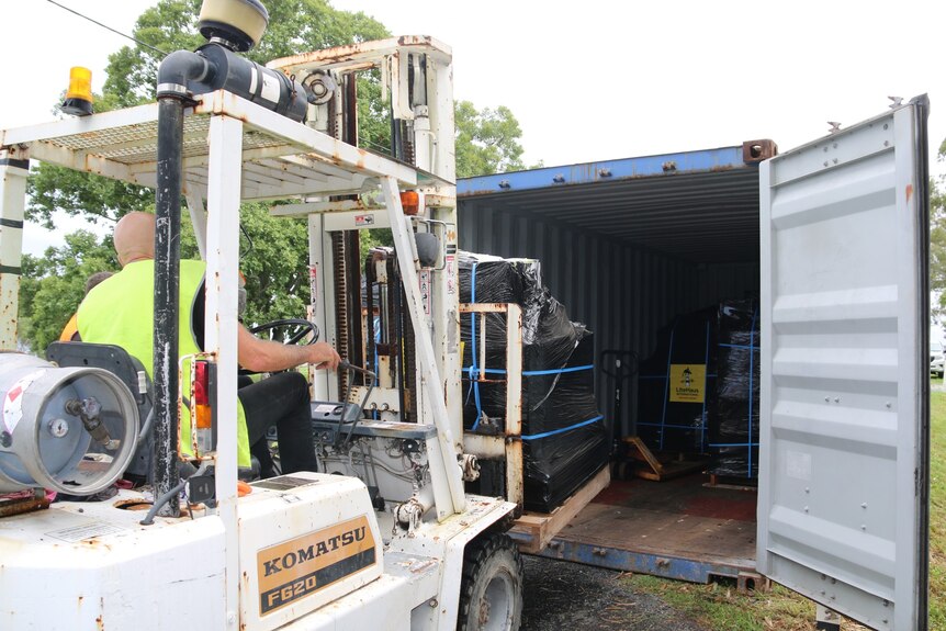 A man loads material into a shipping container.