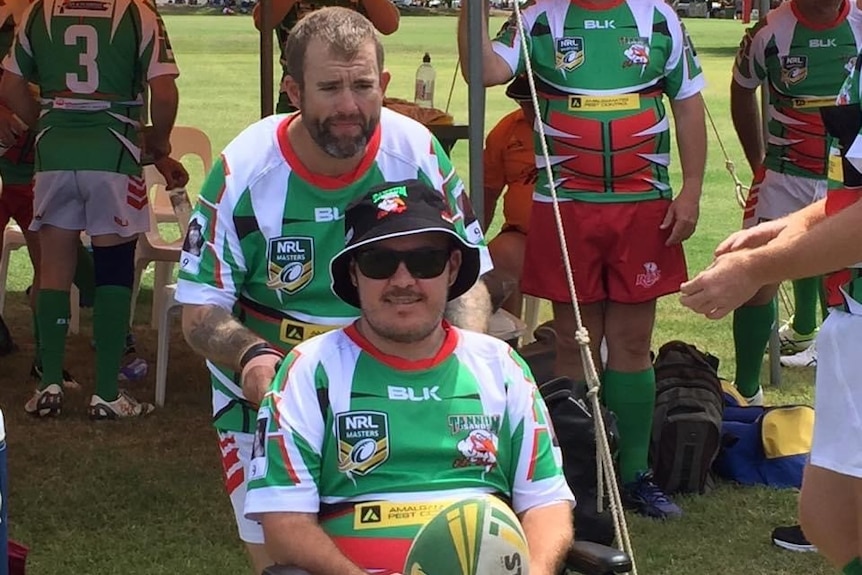 Matt Downey in his football uniform sitting, a team mate behind him.