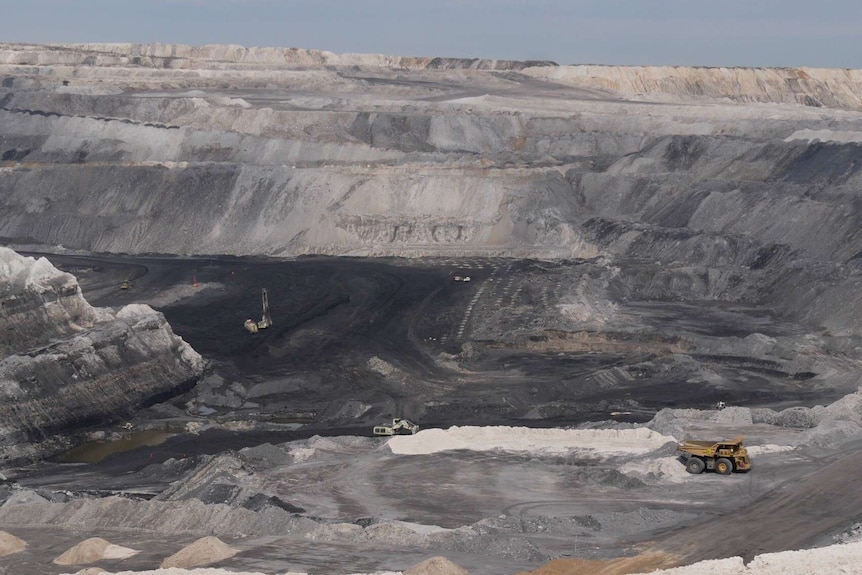 A wide shot of a huge mine site with a truck in it.