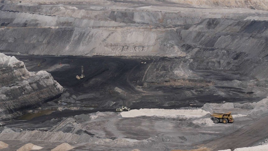 Huge open cut mining pit with whitish soil on the top layers and black coal at the bottom