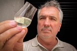 William McHenry examining a glass of his alcoholic product.