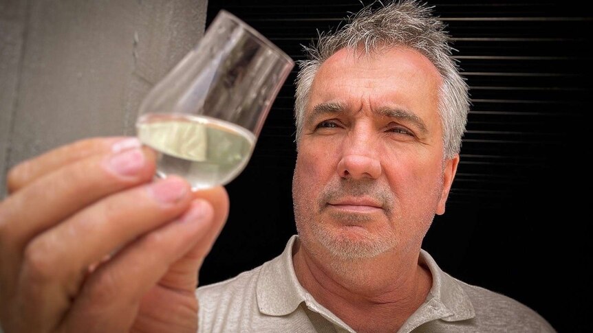 William McHenry examining a glass of his alcoholic product.