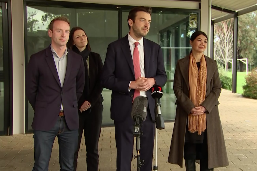 Two women and three men standing under a verandah