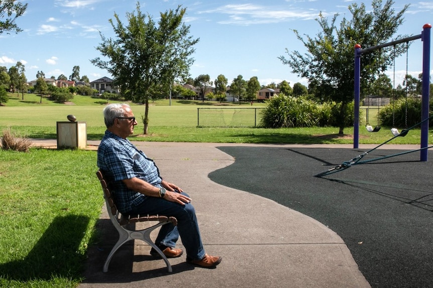 A man sitting on a chair in a playground.