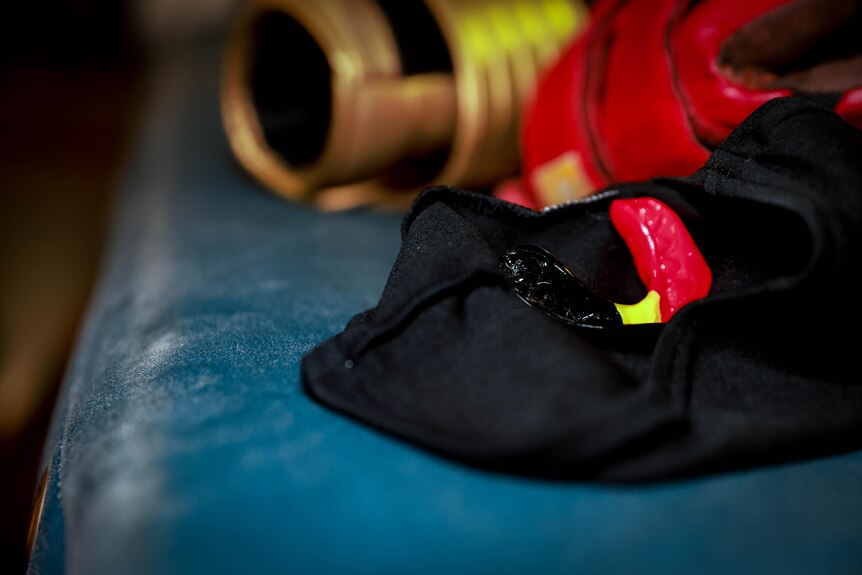 A black, yellow, red coloured mouthguard in laying on the edge of a boxing ring