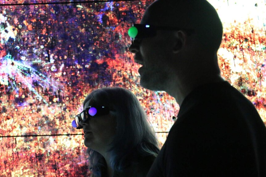 Two people wearing dark glasses, shadowed against map of Mars.