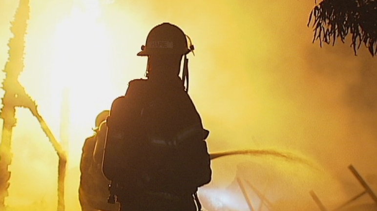 A fire fighter in silhouette against flames