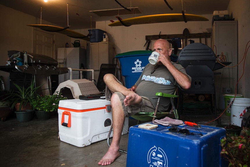 David Burkhardt drinks coffee in a camper chair in his garage