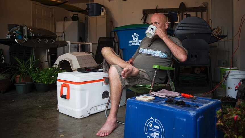 David Burkhardt drinks coffee in a camper chair in his garage