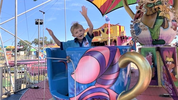 boy in school uniform takes a merry-go-round ride in a teacup 