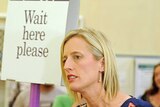 ACT Labor leader Katy Gallagher stands next to a 'Wait here please' sign to cast her ballot on October 20, 2012.