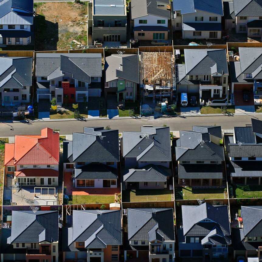An aerial photo of the red, orange and grey roofs in an housing estate.