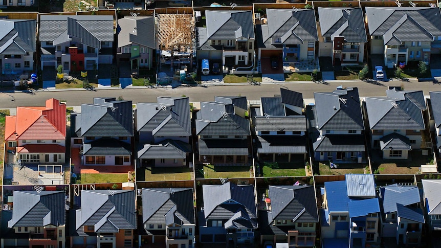 An aerial photo of the red, orange and grey roofs in an housing estate.