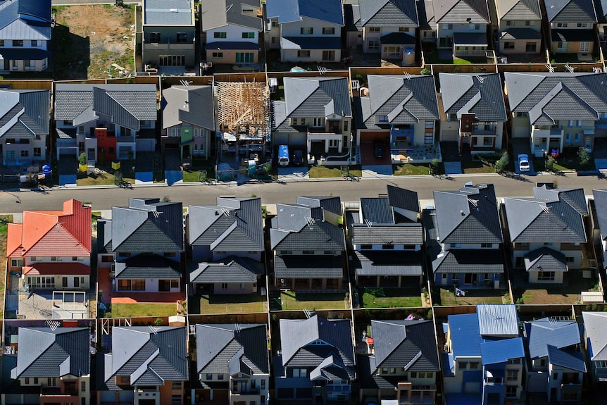 An aerial photo of the red, orange and grey roofs in an housing estate.