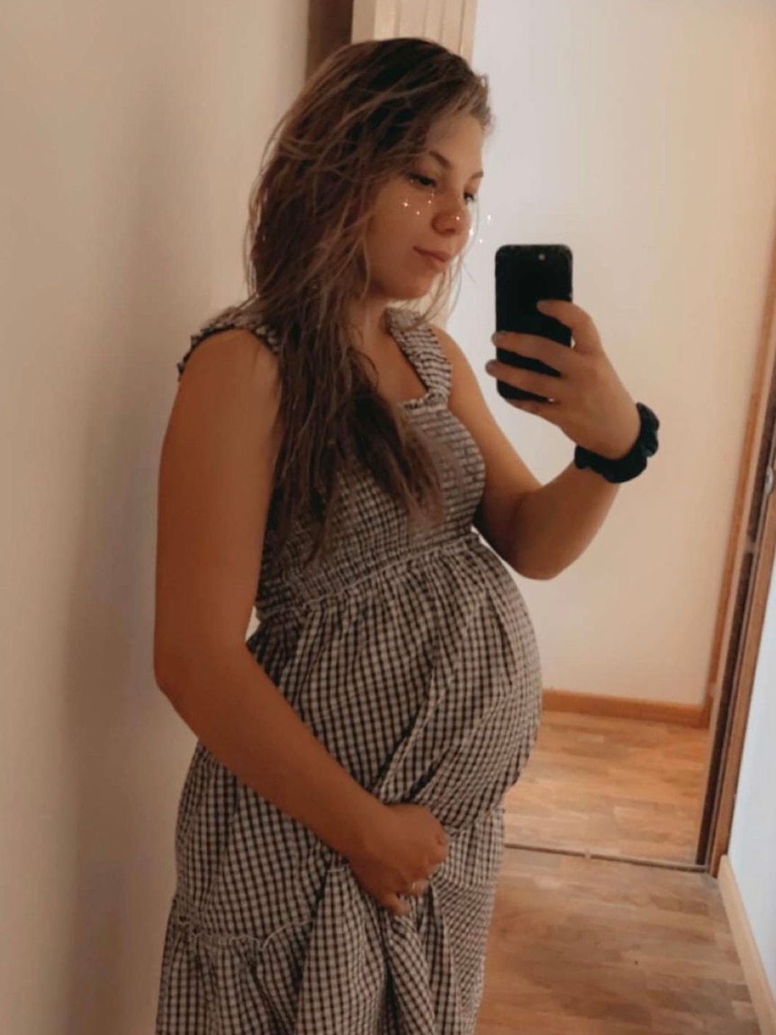 Pregnant woman standing in front of mirror