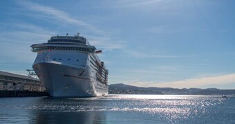 A large ship docked on a sunny day with light reflecting off the water