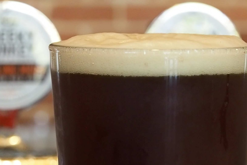 Close up of a freshly poured pint of dark beer on the bar