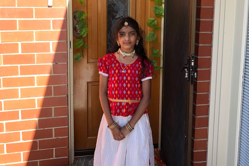 A young girl standing in front of door