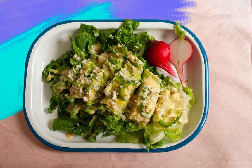 A chopped Caesar salad in an enamel serving dish, topped with dressing, jalapeno and pecorino cheese makes an easy side recipe.