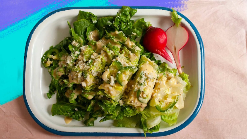 A chopped Caesar salad in an enamel serving dish, topped with dressing, jalapeno and pecorino cheese makes an easy side recipe.