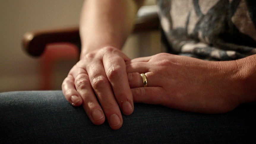 Some hands folded on someone's knee.