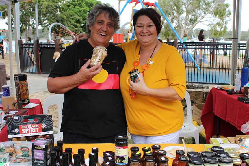 Two people at a market stall holding products