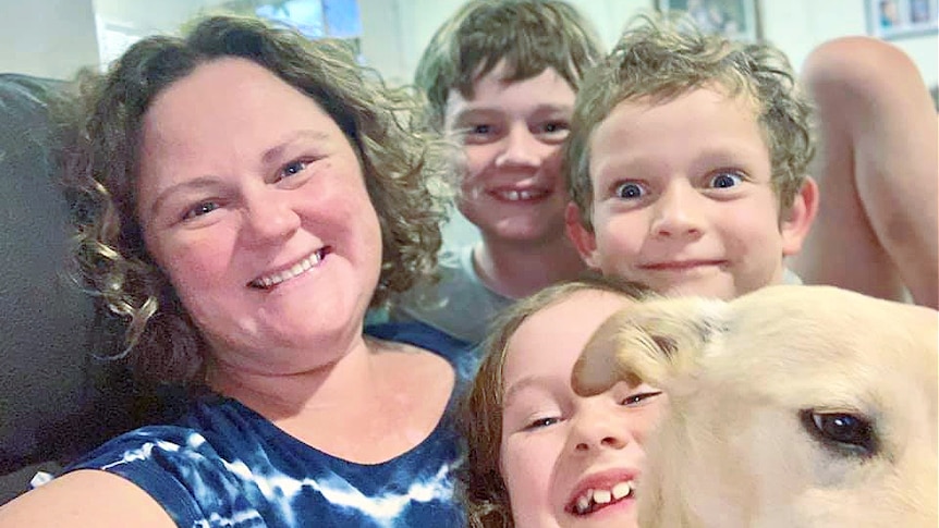 A woman and her three children smile at the camera.