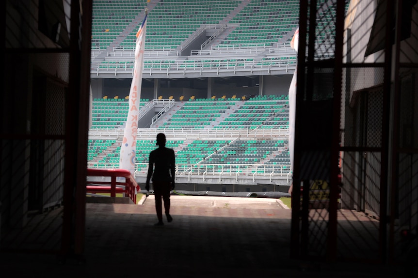 A worker is silhouetted against spectators seats at Gelora Bung Tomo Stadium.
