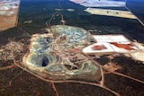 An aerial view of a gold mining operation with an open pit and processing plant.
