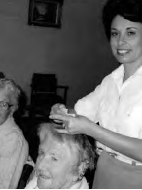 A black and white photo of a woman cutting hair