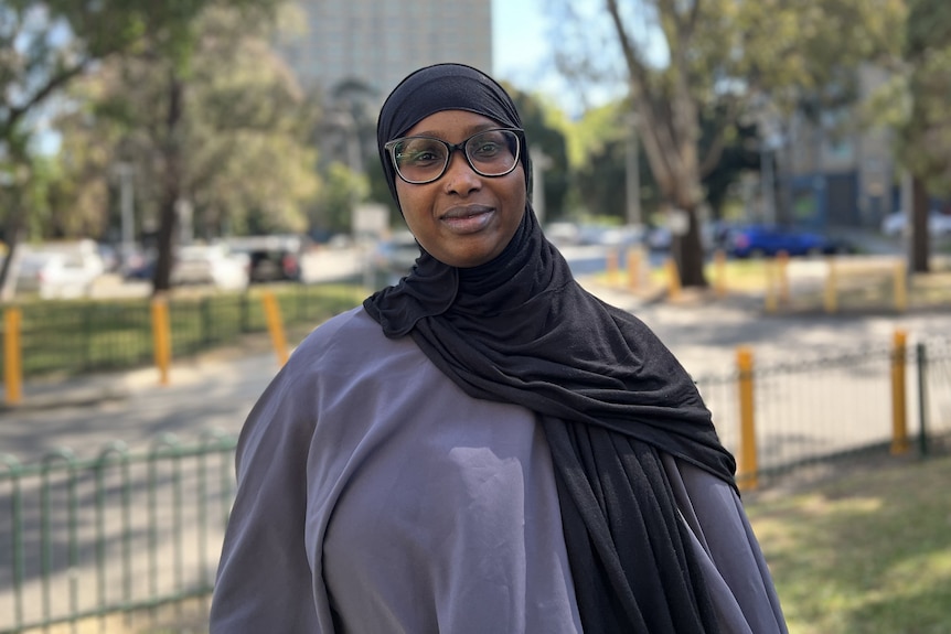 A woman wearing glasses and a black hijab.