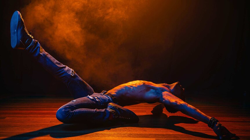 A dramatic colour close-up photo of Dashaun Wesley in a dance pose in front of dark background.