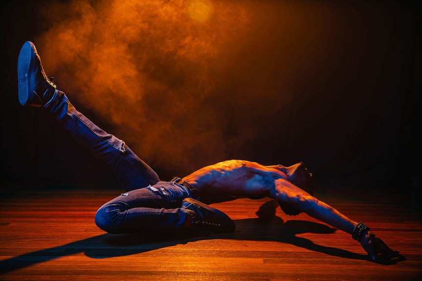 A dramatic colour close-up photo of Dashaun Wesley in a dance pose in front of dark background.