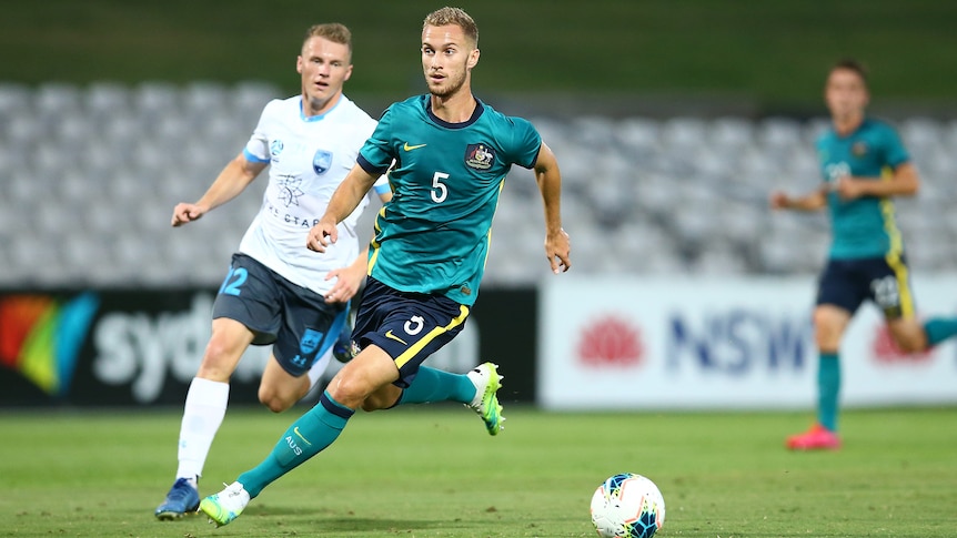 Soccer player kicking the ball with defender behind him during a match