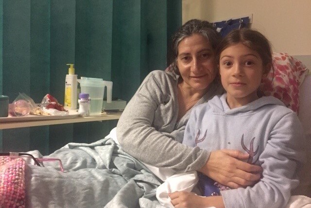 A woman in a hospital bed with her around a young girl.