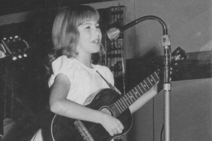 Lori Balmer, aged 7 performs live on stage with a guitar.