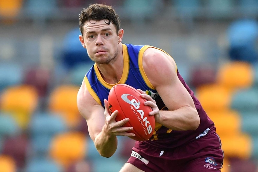 A Brisbane Lions AFL player holds the ball in both hands during a match against Fremantle at the Gabba.