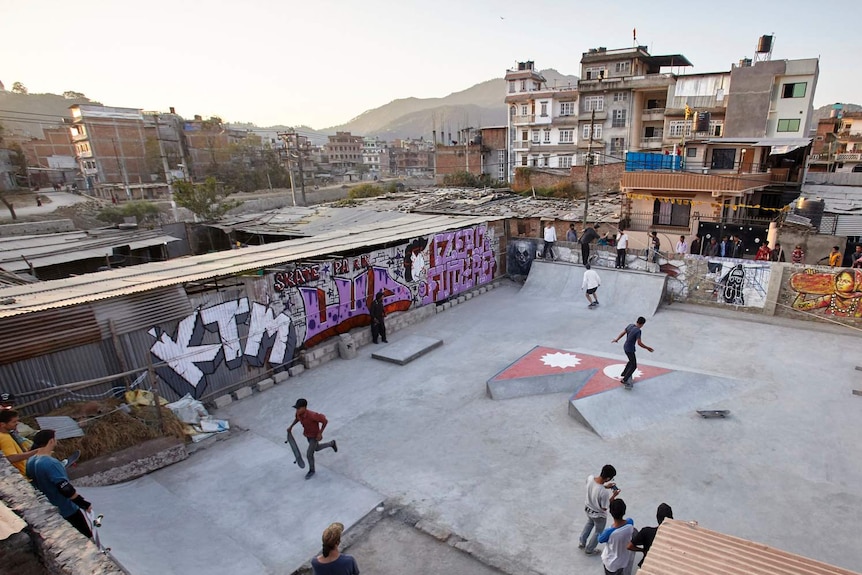 A skatepark in a dense urban environment, with skaters riding the ramps.