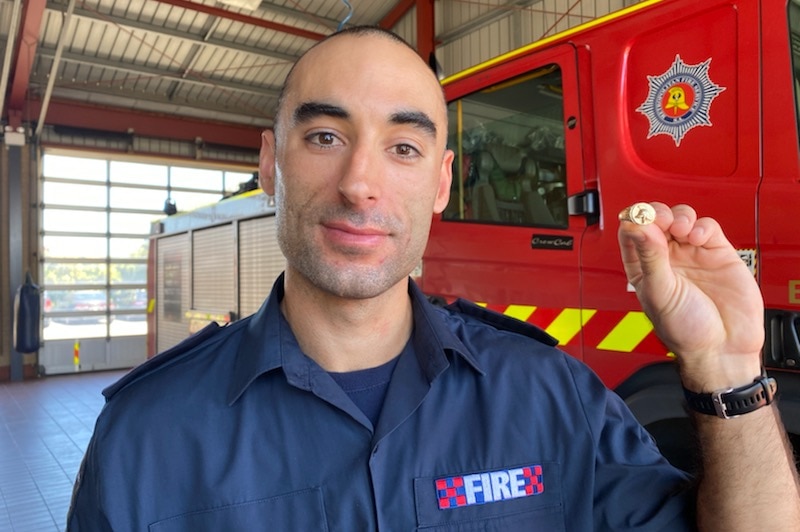 A firefighter holding up a gold ring.