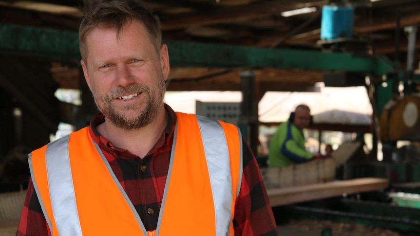 Tasmanian sawmiller, Matthew Torenius, wears an orange hivis vest over his flannelette shirt.