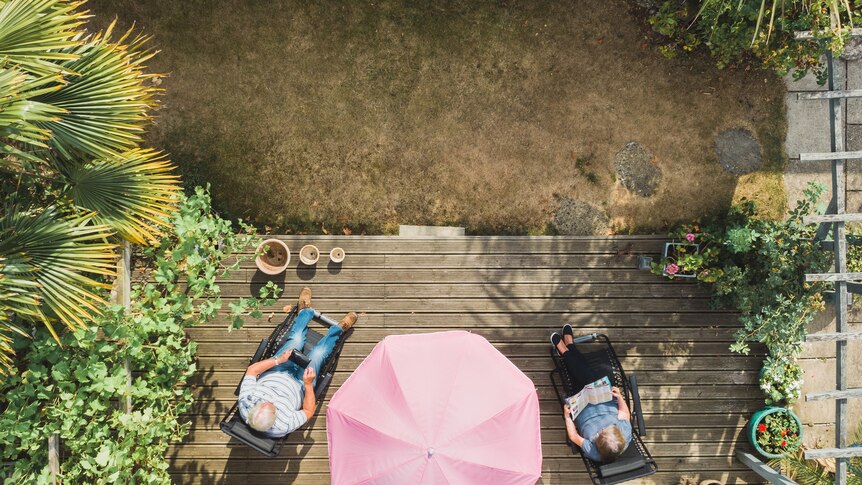 Bird's eye view photo of two older people sitting on a deck with their feet up