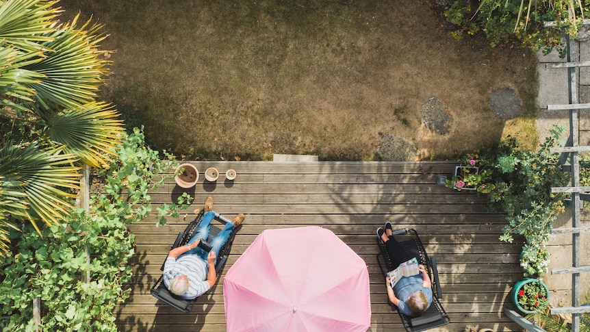 Bird's eye view photo of two older people sitting on a deck with their feet up